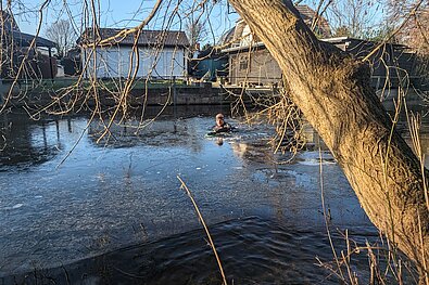 SwimRun: Man swimming on ice in front of houses © SCC EVENTS / private 
