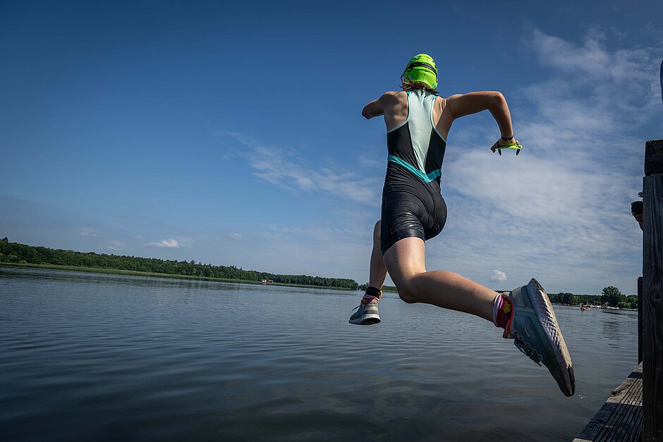 SwimRun: Teilnehmer:in springt vom Holzsteg ins Wasser © SCC EVENTS / Tilo Wiedensohler