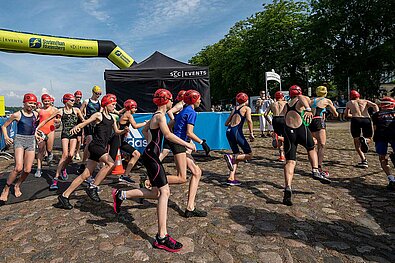 SwimRun Rheinsberg 2022: Mädchen und Jungen laufen den applaudierenden Zuschauern entgegen 