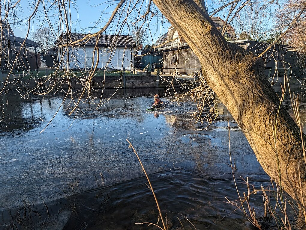 SwimRun: Man swimming on ice in front of houses © SCC EVENTS / privat