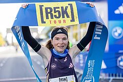 Läuferin des r5k hält Zielband mit Aufdruck des r5k-Logos über ihren Kopf.