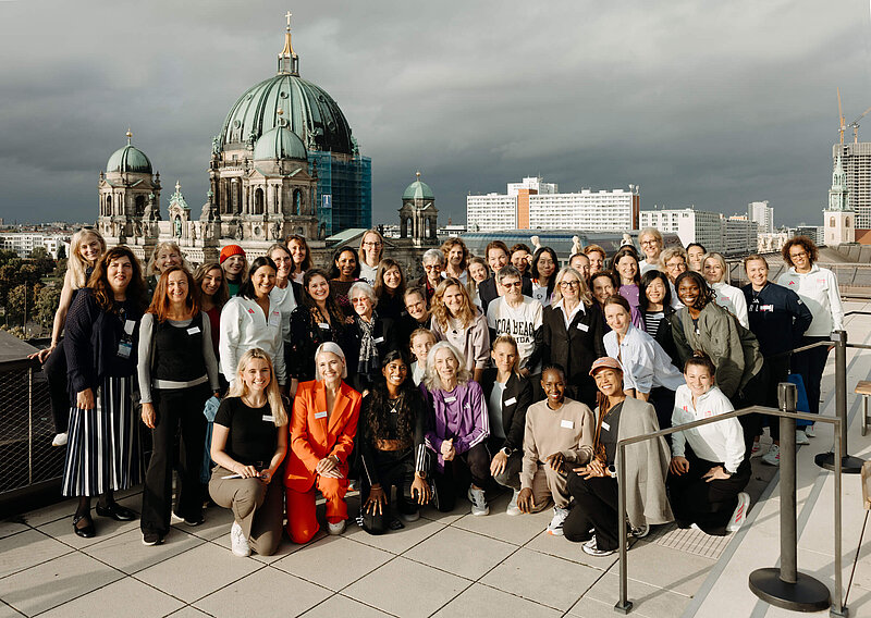 Gruppenfoto internationaler Läuferinnen; im Hintergrund der Berliner Dom.
